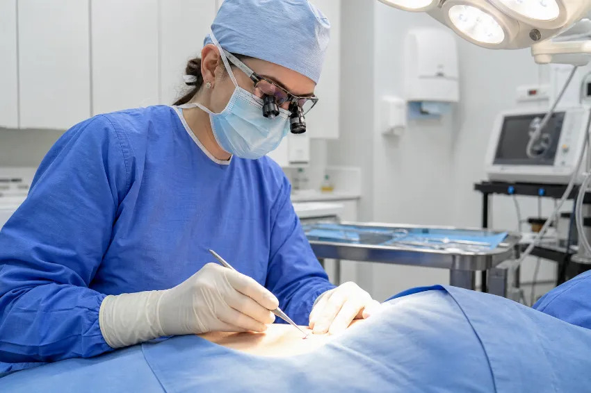 Dermatolog kirurg med izvajanjem biopsije sumljivega kožnega tkiva v sodobni in čisti ambulanti.